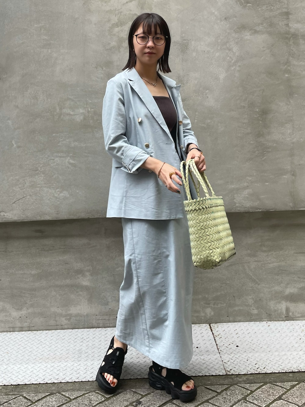 ブルー系のテーラードジャケット、ブルー系のスカート、グリーン系のバッグを着用したレディースの春コーディネートの3枚目の写真
