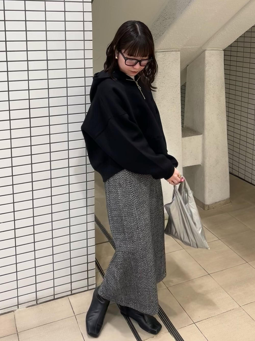 ブラック系のパーカー、ホワイト系のスカートを着用したレディースの冬コーディネートの3枚目の写真