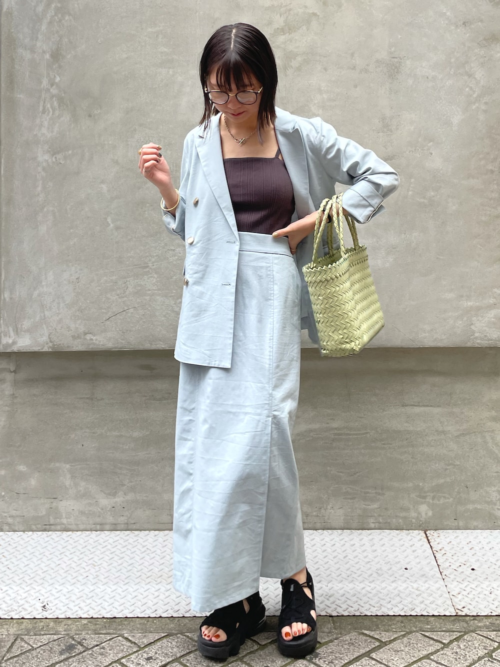 ブルー系のテーラードジャケット、ブルー系のスカート、グリーン系のバッグを着用したレディースの春コーディネートの2枚目の写真