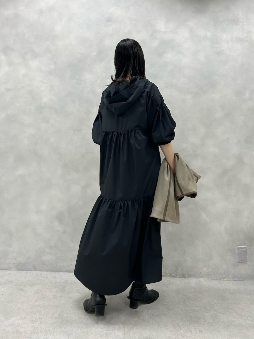 ベージュ系のノーカラーコート、ブラック系のワンピースを着用したレディースの冬コーディネートの3枚目の写真