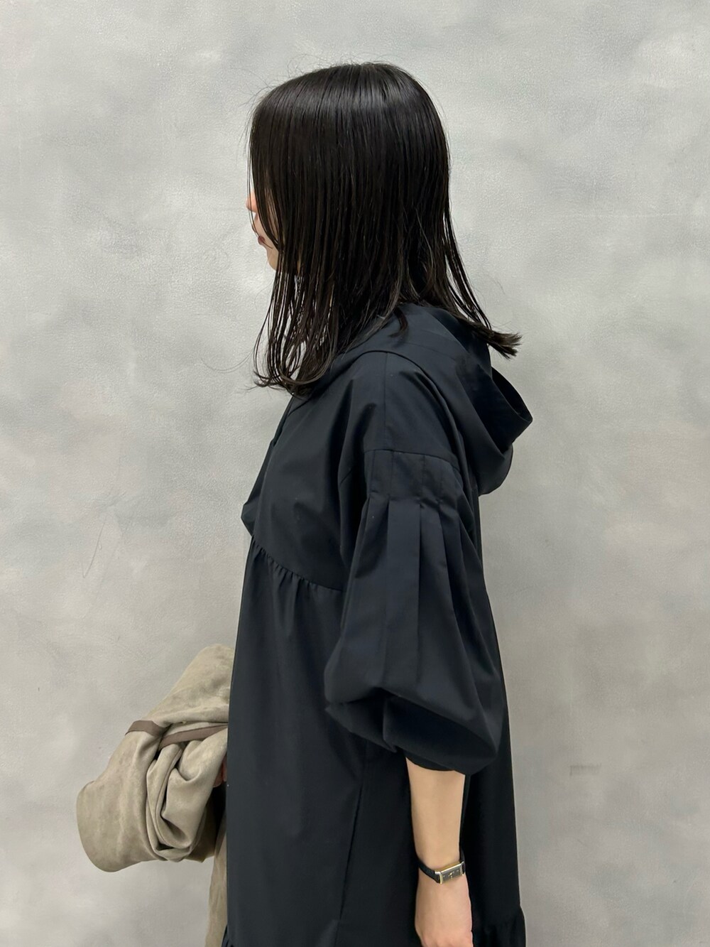 ベージュ系のノーカラーコート、ブラック系のワンピースを着用したレディースの冬コーディネートの2枚目の写真