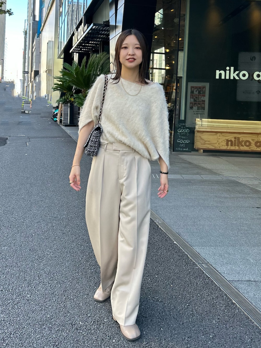 ホワイト系のニット/セーター、ベージュ系のパンツ、その他のショルダーバッグを着用したレディースの秋コーディネートの2枚目の写真