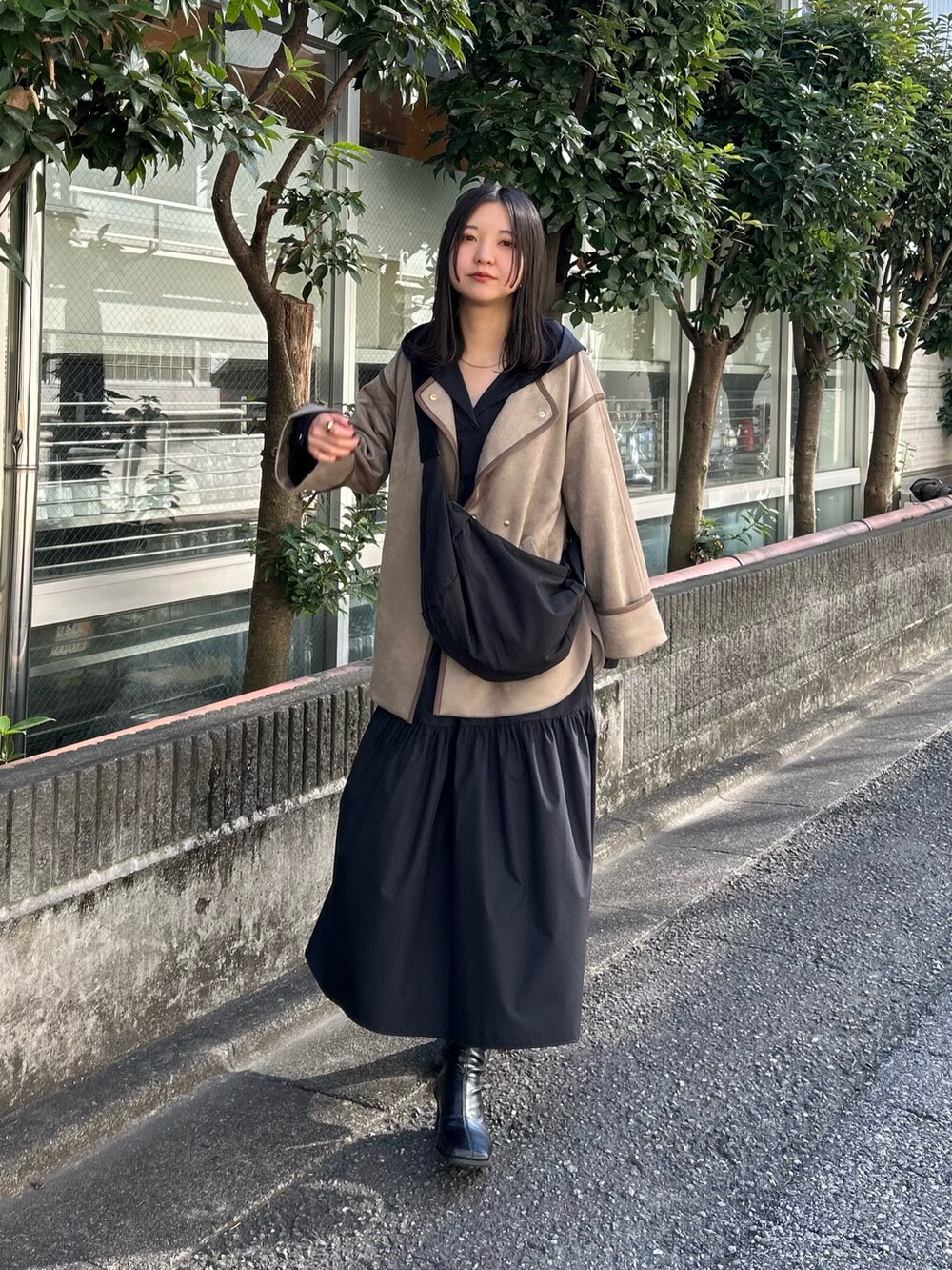 ベージュ系のノーカラーコート、ブラック系のワンピースを着用したレディースの冬コーディネートの4枚目の写真