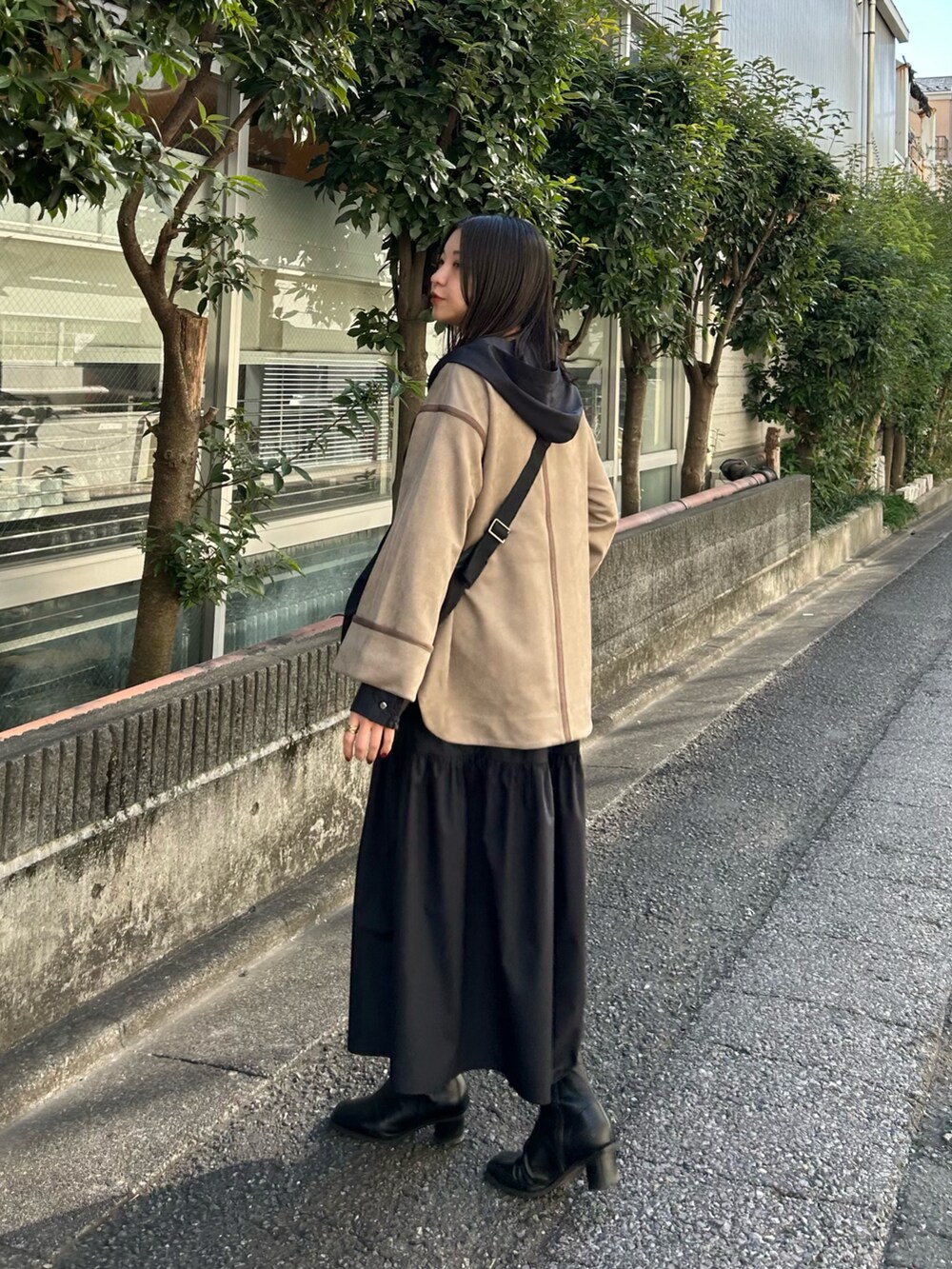 ベージュ系のノーカラーコート、ブラック系のワンピースを着用したレディースの冬コーディネートの5枚目の写真