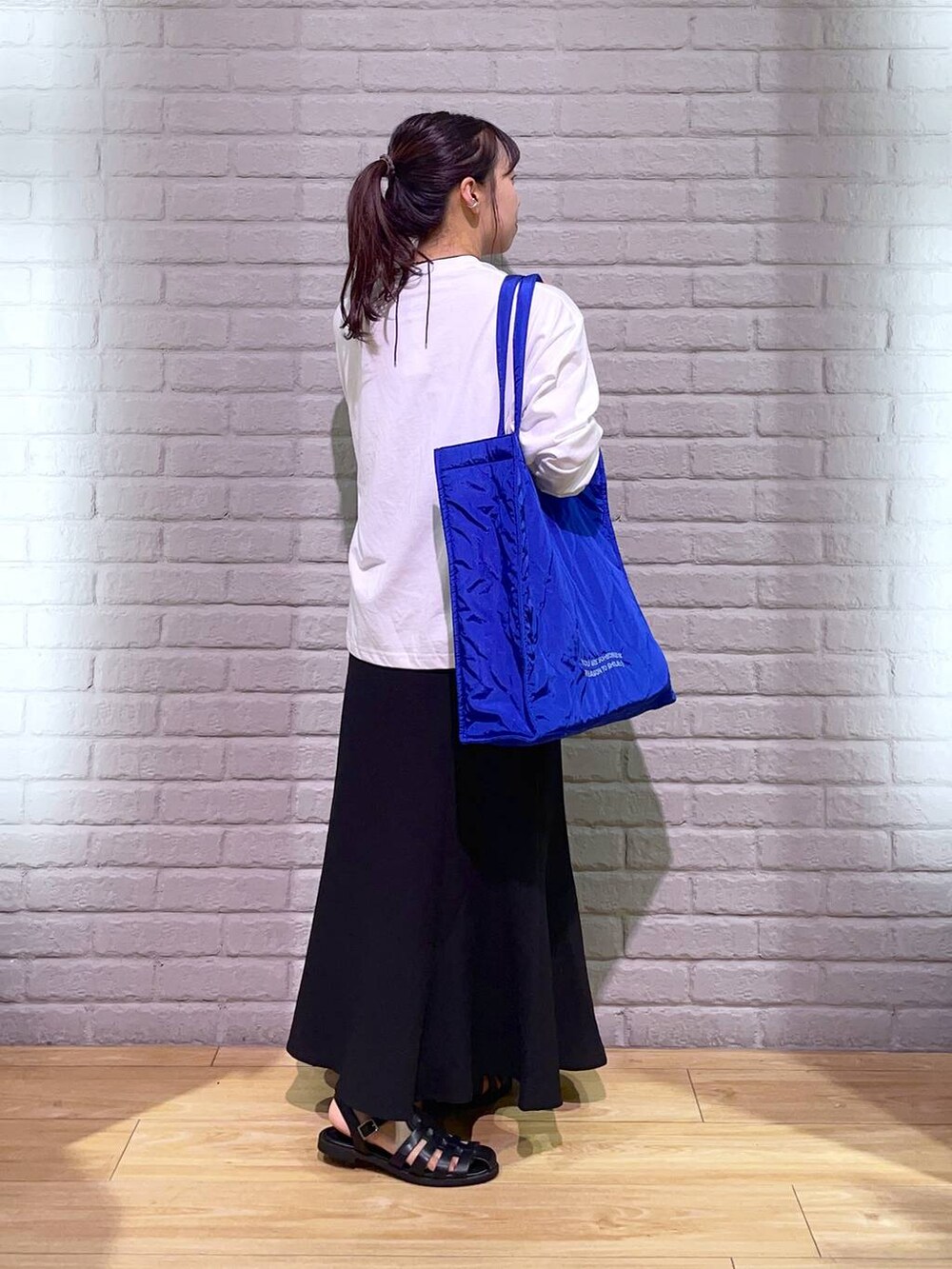 ブラック系のサンダル、ブラック系のスカート、ブルー系のショルダーバッグを着用したレディースの夏コーディネートの3枚目の写真