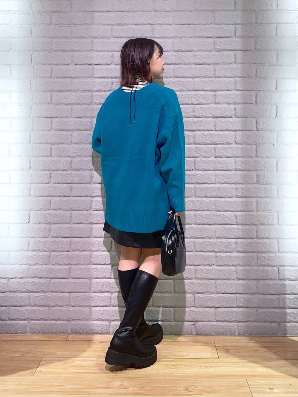 ホワイト系のTシャツ/カットソー、グリーン系のニット/セーター、ブラック系のスカートを着用したレディースの秋コーディネートの3枚目の写真