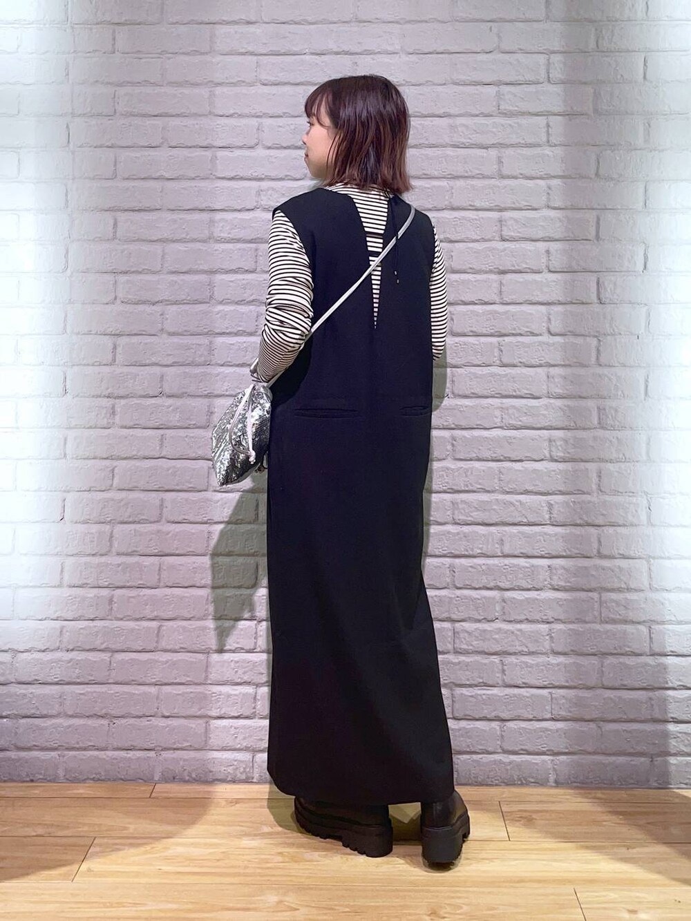 ホワイト系のTシャツ/カットソー、ブラック系のワンピース、ブラック系のブーツを着用したレディースの秋コーディネートの3枚目の写真