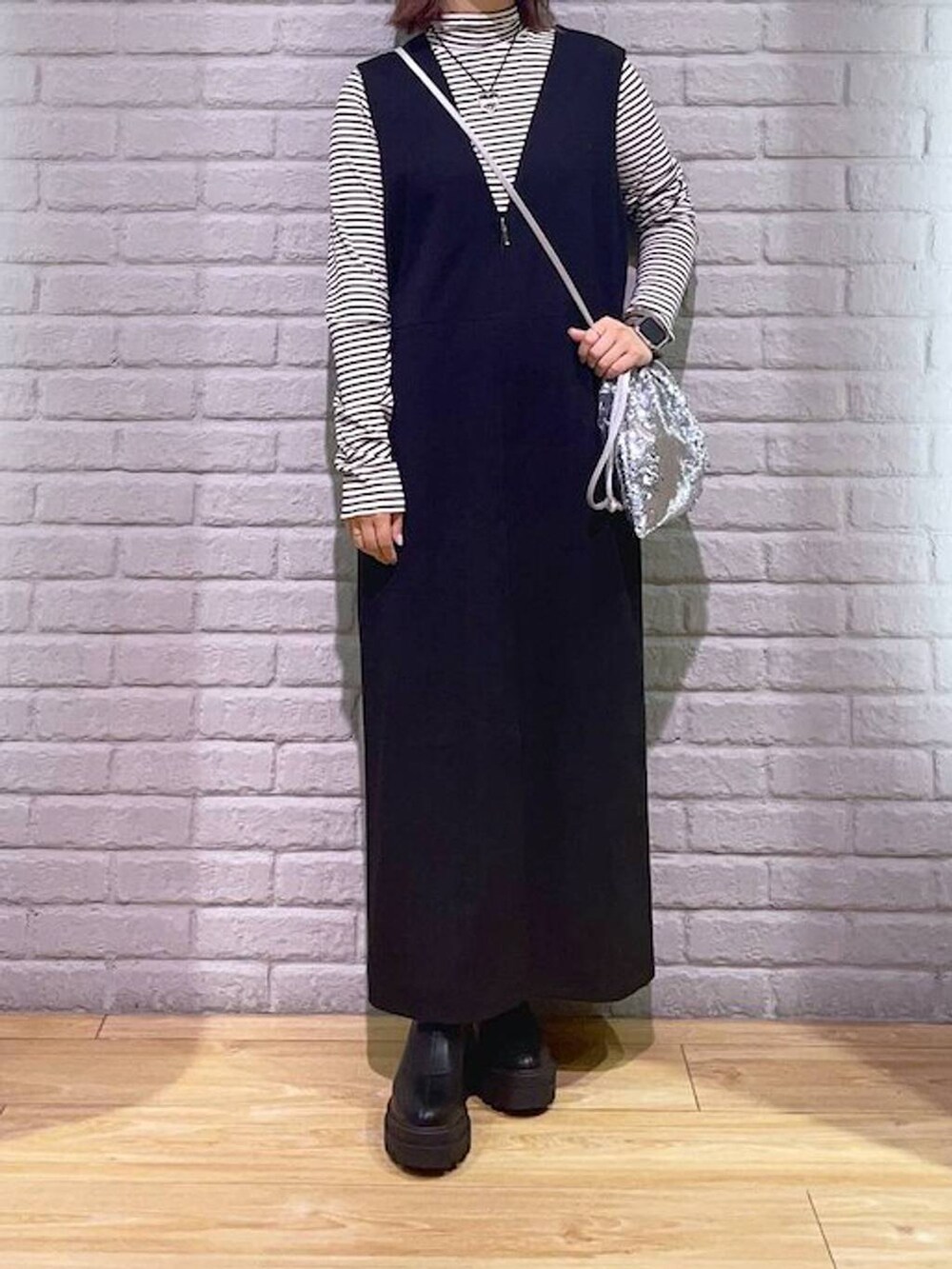 ホワイト系のTシャツ/カットソー、ブラック系のワンピース、ブラック系のブーツを着用したレディースの秋コーディネートの2枚目の写真