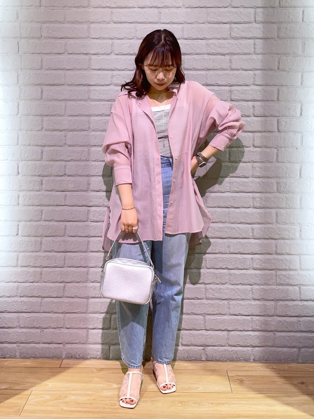 シルバー系のショルダーバッグ、ピンク系のシャツ/ブラウス、ブルー系のデニムパンツを着用したレディースの夏コーディネートの2枚目の写真