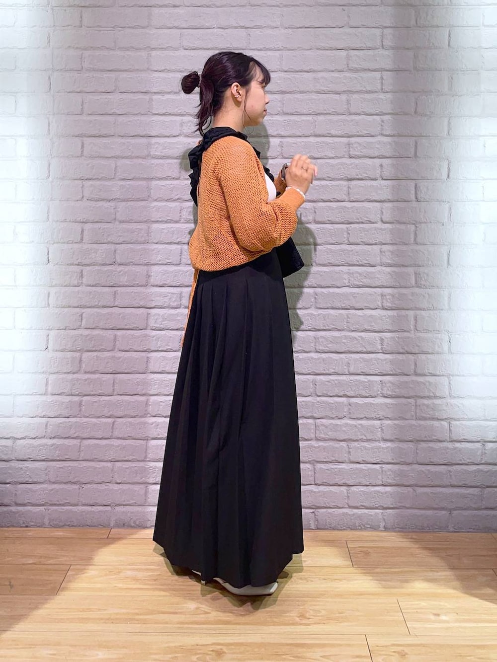 ホワイト系のタンクトップ、ホワイト系のパンプス、ベージュ系のカーディガン/ボレロを着用したレディースの夏コーディネートの2枚目の写真