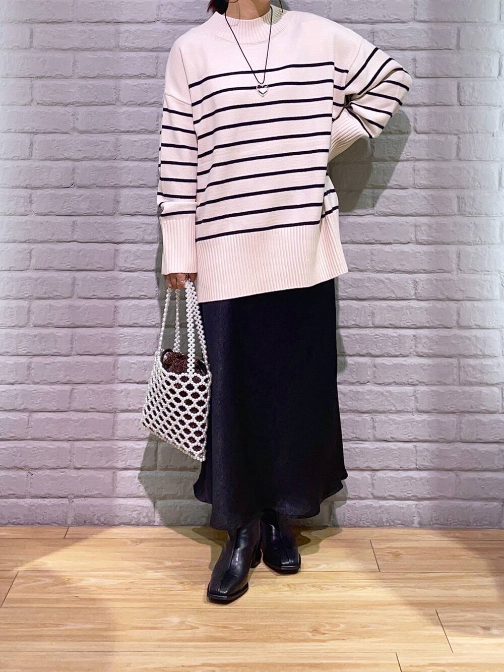 その他のニット/セーター、ブラック系のパンプス、ホワイト系のショルダーバッグを着用したレディースの秋コーディネートの2枚目の写真