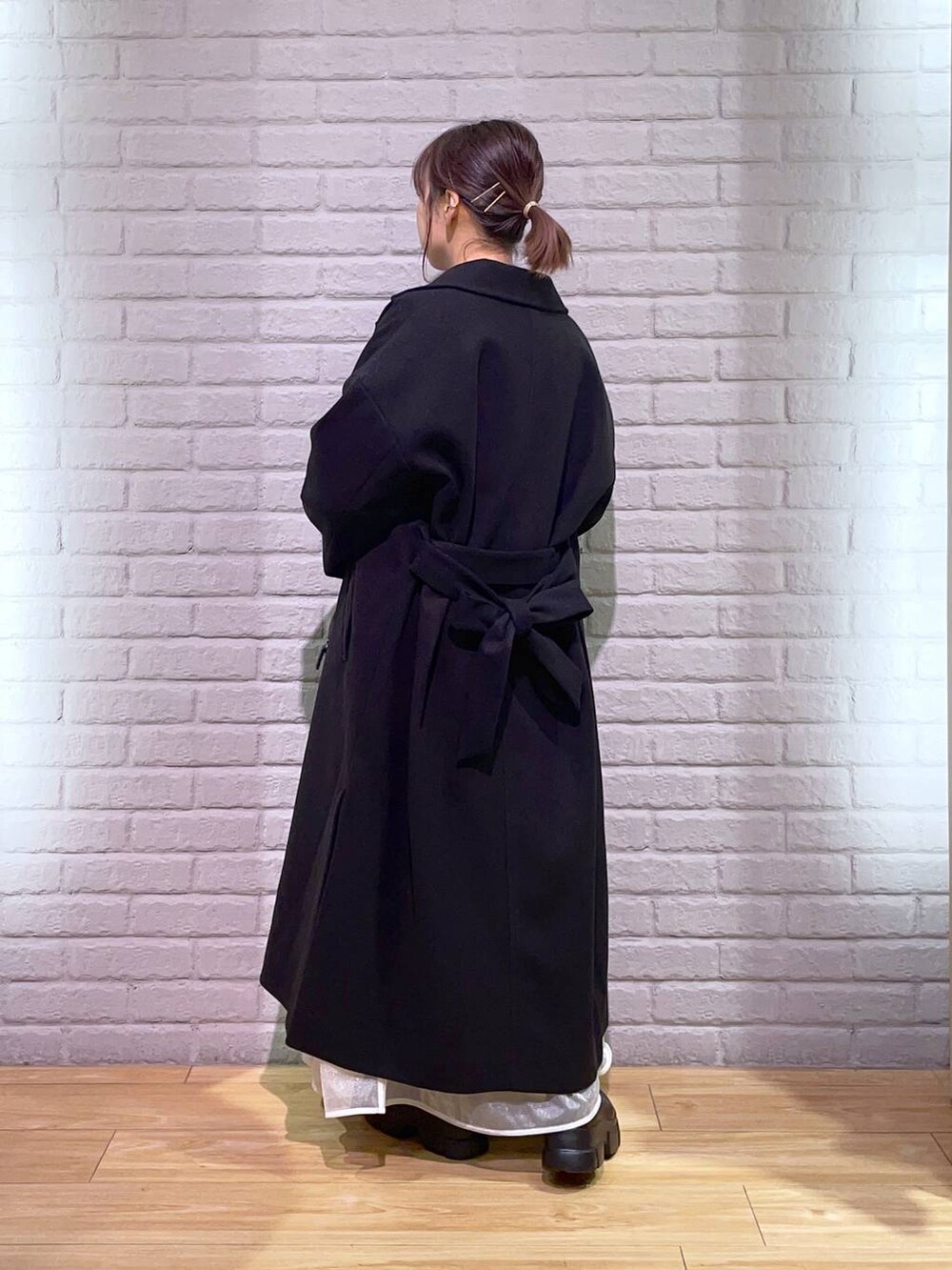 ブラック系のトレンチコート、ブラック系のブーツ、ブラウン系のニット/セーターを着用したレディースの秋コーディネートの3枚目の写真