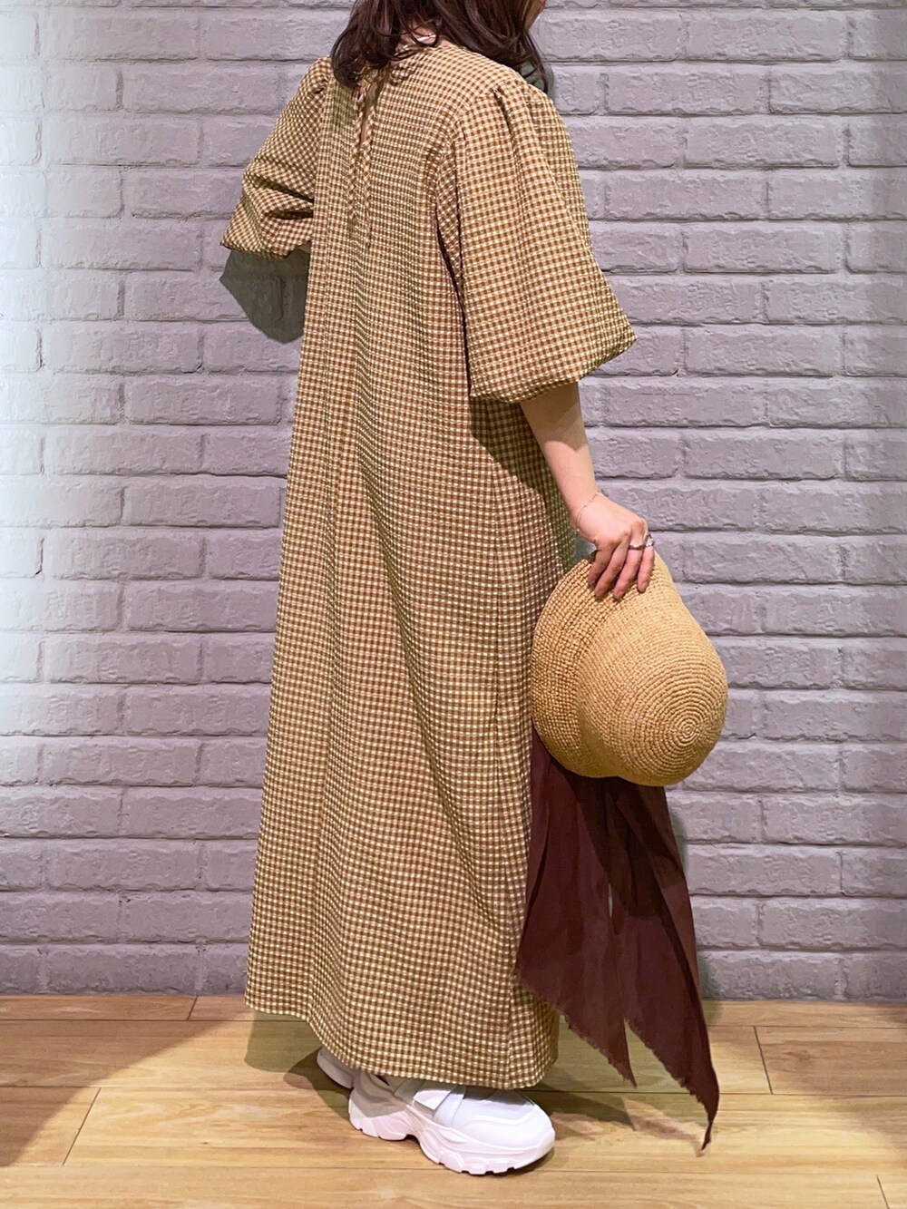 ブラウン系のワンピース、ホワイト系のサンダル、ベージュ系のハットを着用したレディースの春コーディネートの3枚目の写真