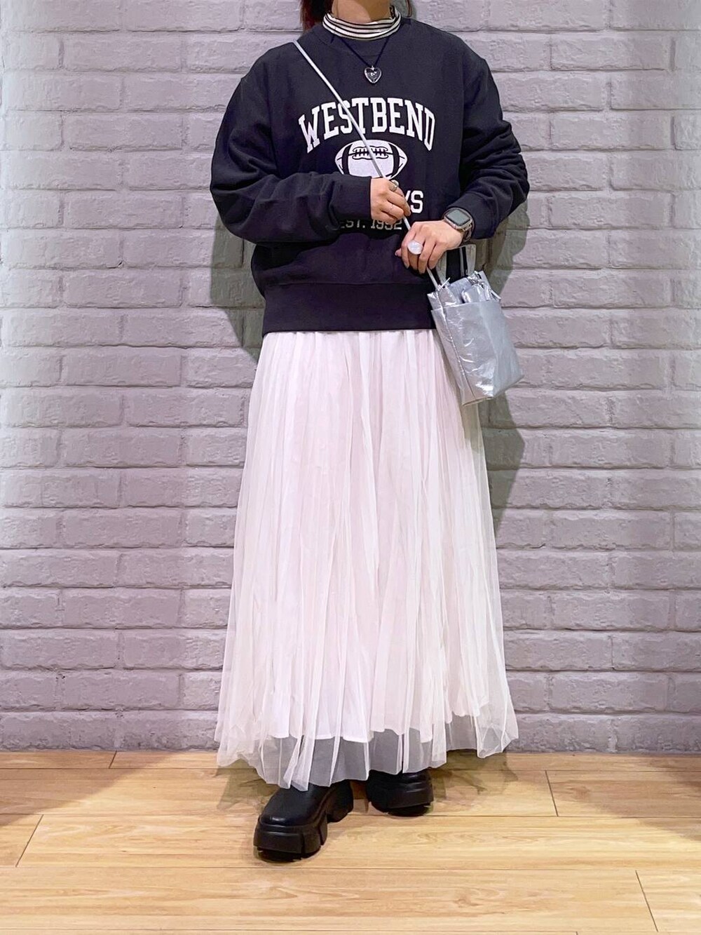 ホワイト系のTシャツ/カットソー、ブラック系のブーツ、シルバー系のショルダーバッグを着用したレディースの秋コーディネートの2枚目の写真