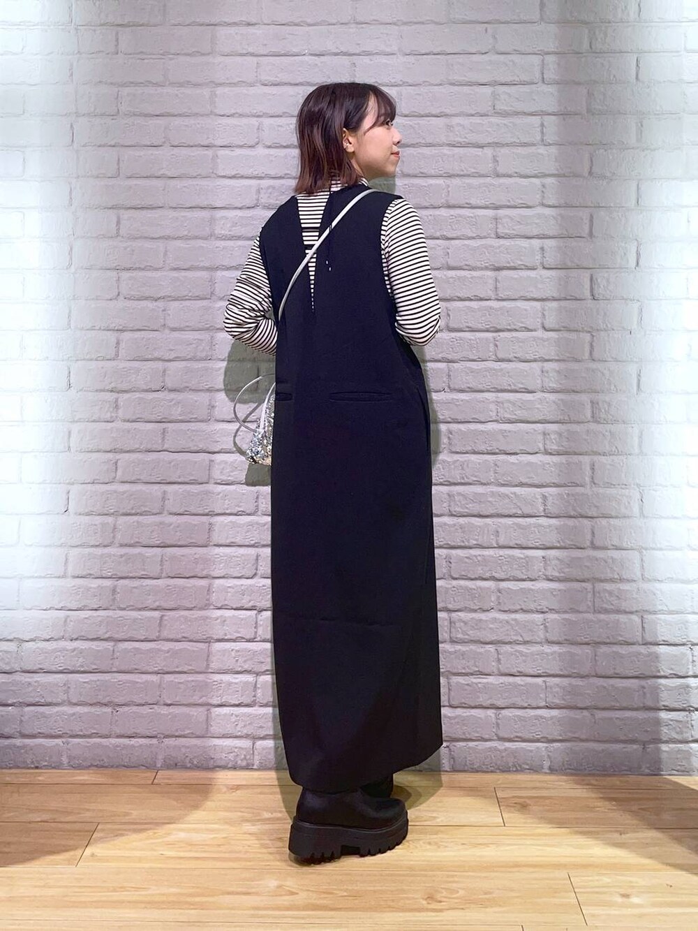 ホワイト系のTシャツ/カットソー、ブラック系のワンピース、ブラック系のブーツを着用したレディースの秋コーディネートの4枚目の写真