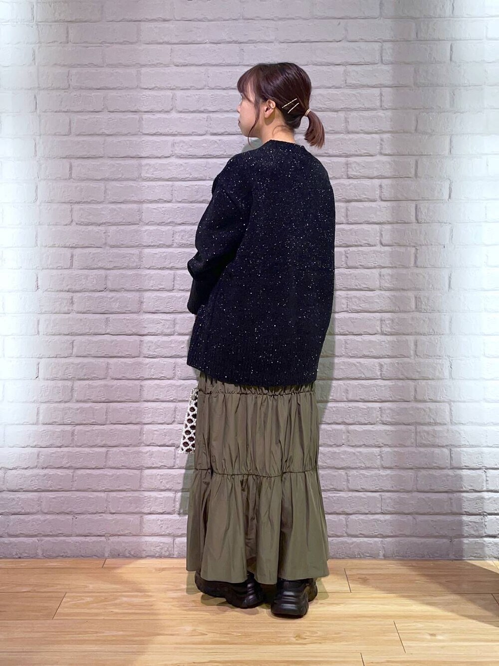 ホワイト系のショルダーバッグ、ブラック系のニット/セーター、ブラック系のスニーカーを着用したレディースの秋コーディネートの4枚目の写真