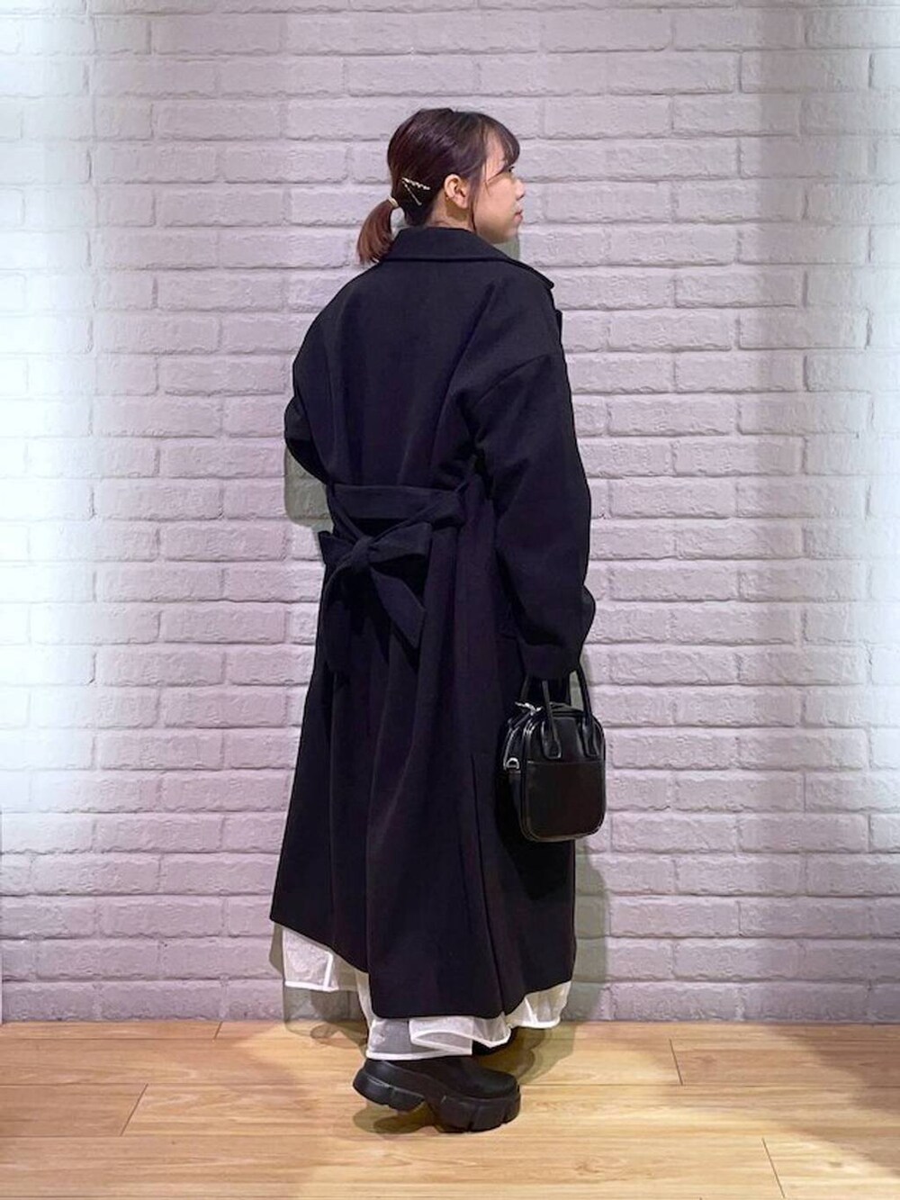 ブラック系のトレンチコート、ブラック系のブーツ、ブラウン系のニット/セーターを着用したレディースの秋コーディネートの4枚目の写真