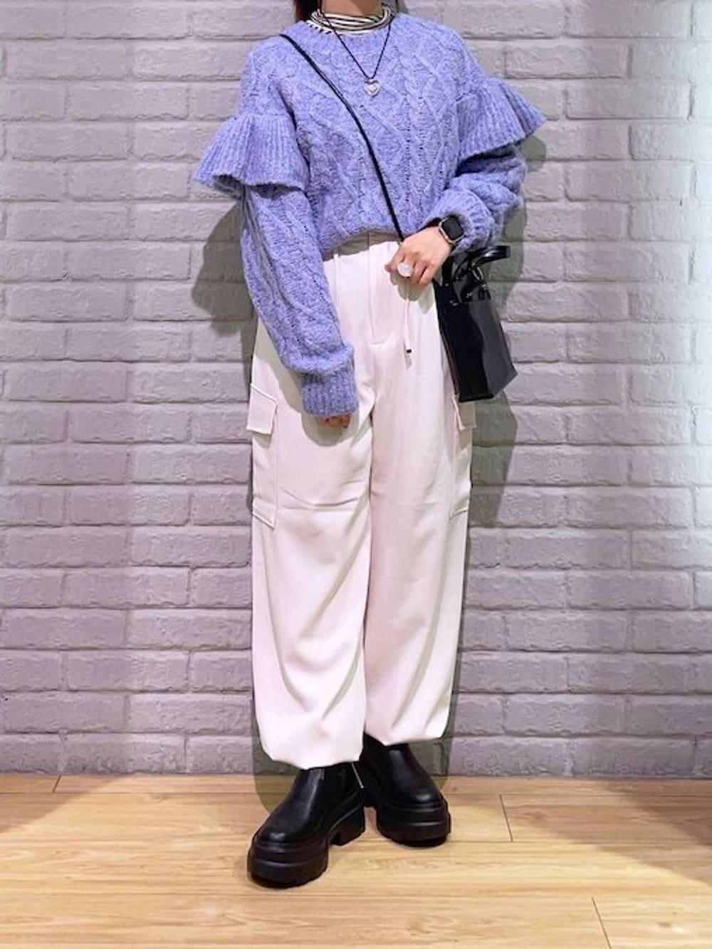 ホワイト系のTシャツ/カットソー、パープル系のニット/セーター、ブラック系のブーツを着用したレディースの秋コーディネートの2枚目の写真