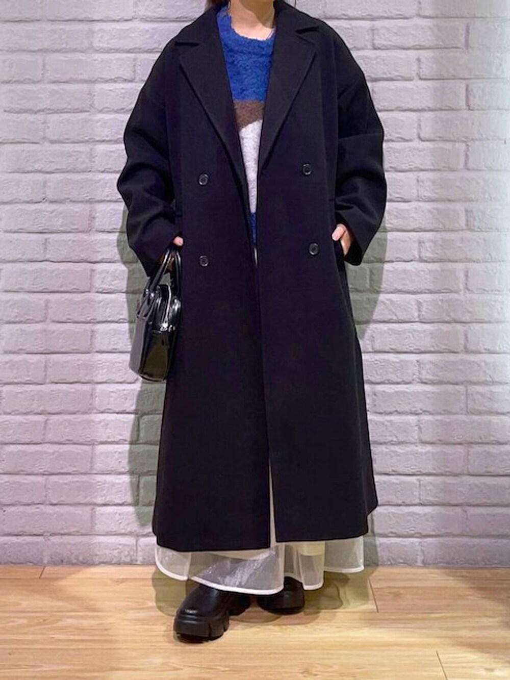 ブラック系のトレンチコート、ブラック系のブーツ、ブラウン系のニット/セーターを着用したレディースの秋コーディネートの2枚目の写真