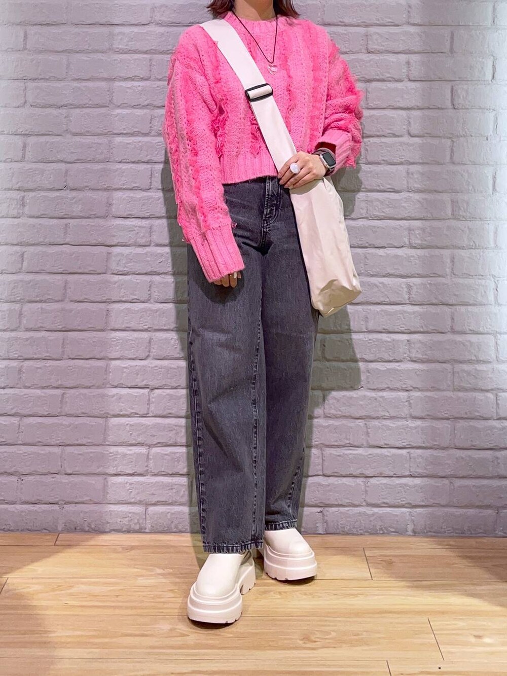 ホワイト系のボディバッグ/ウエストポーチ、ブラック系のデニムパンツ、ホワイト系のブーツを着用したレディースの秋コーディネートの2枚目の写真