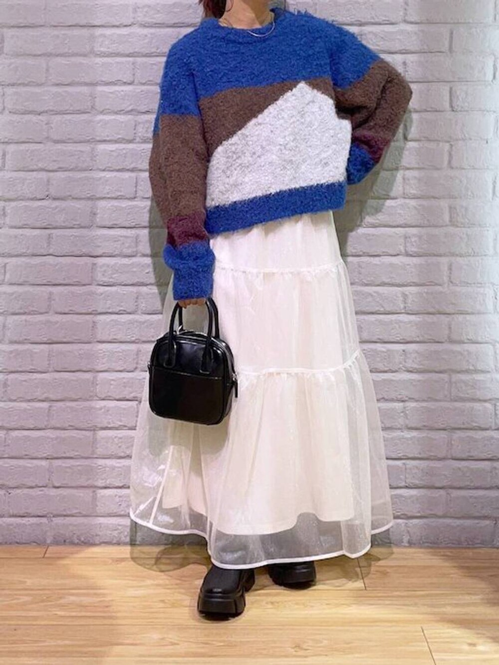 ブラック系のブーツ、ブラウン系のニット/セーター、ブラック系のボストンバッグを着用したレディースの秋コーディネートの2枚目の写真