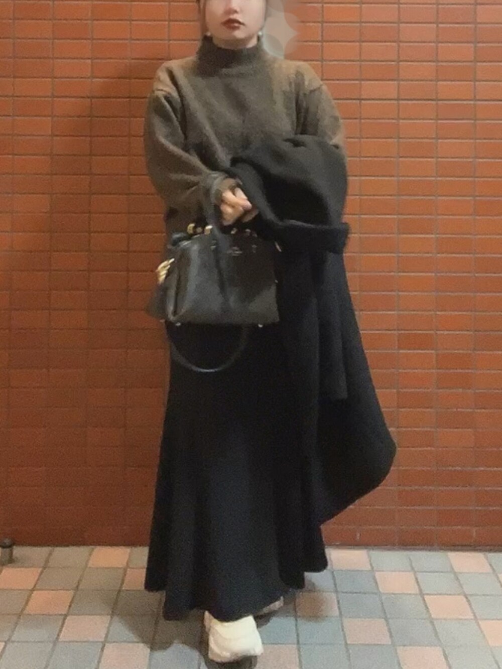 ブラウン系のショルダーバッグ、ブラウン系のニット/セーター、ブラック系のスカートを着用したレディースの秋コーディネートの3枚目の写真