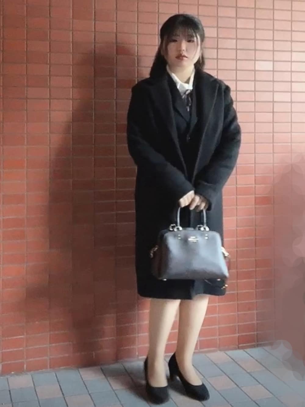 ブラウン系のショルダーバッグ、ブラック系のパンプス、ブラック系のチェスターコートを着用したレディースの秋コーディネートの2枚目の写真