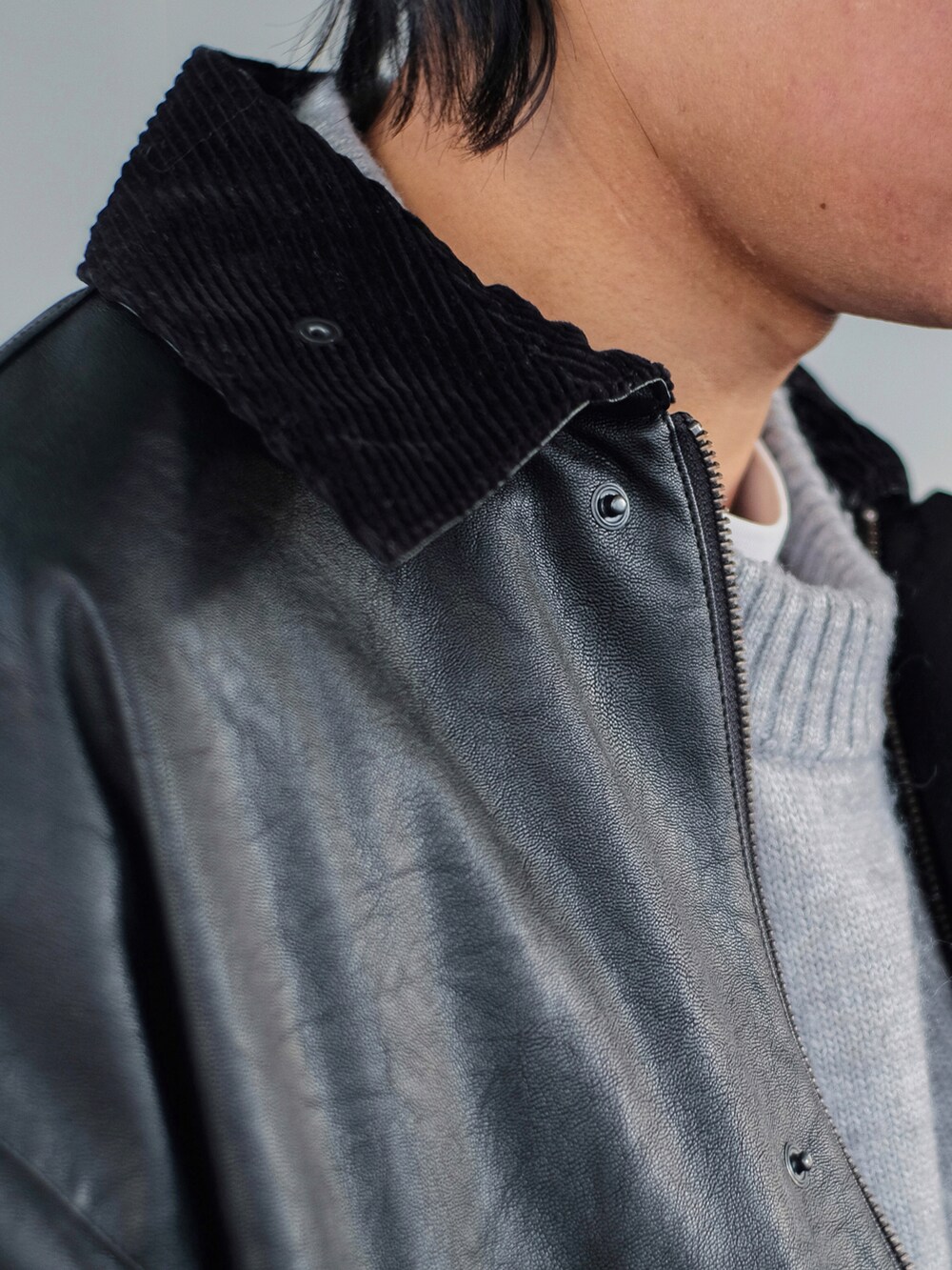 ブラック系のミリタリージャケット、グレー系のニット/セーター、ブルー系のデニムパンツを着用したメンズの冬コーディネートの4枚目の写真