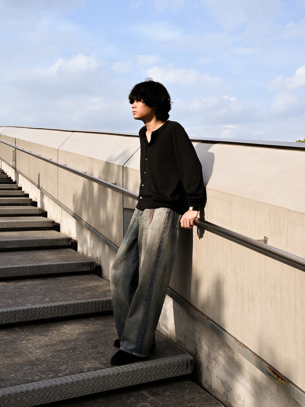 ブルー系のデニムパンツ、ブラック系のブーツ、ブラック系のカーディガン/ボレロを着用したメンズの春コーディネートの5枚目の写真