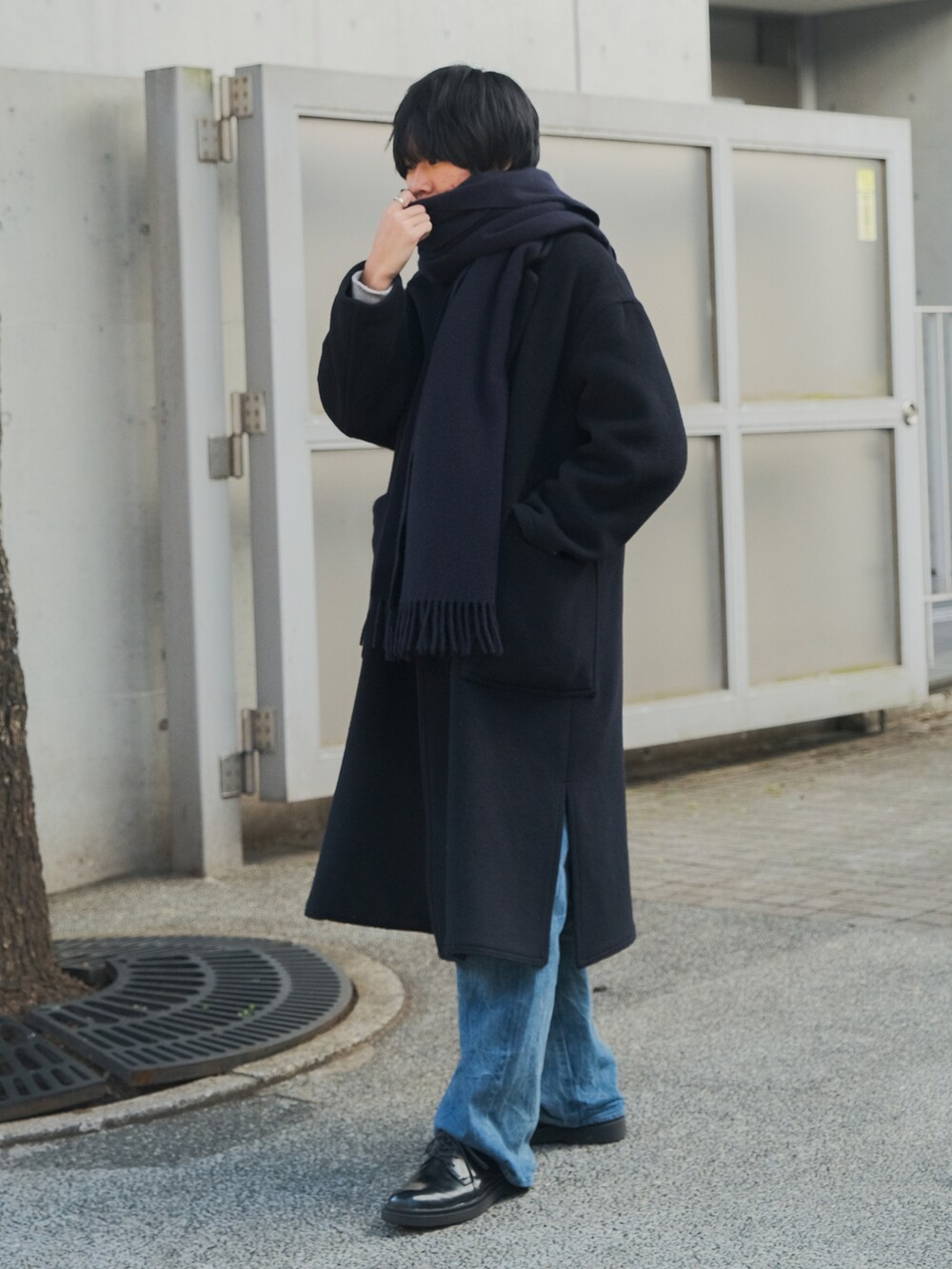 ブルー系のチェスターコート、ブルー系のデニムパンツ、ブラック系のドレスシューズを着用したメンズの冬コーディネートの2枚目の写真