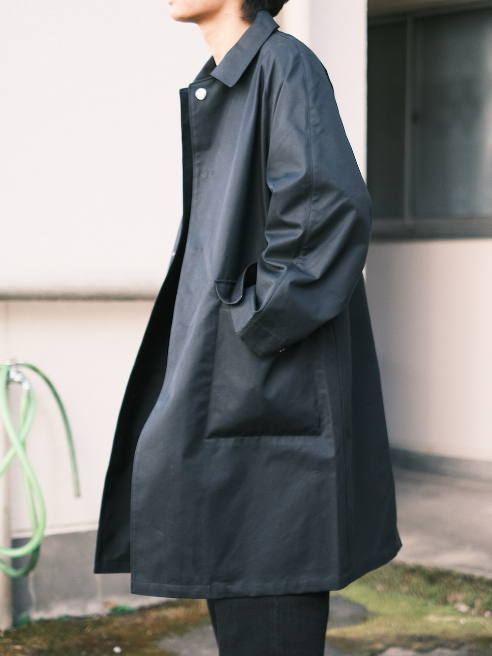 ブラック系のステンカラーコート、ブラック系のデニムパンツ、ブラック系のTシャツ/カットソーを着用したメンズの秋コーディネートの3枚目の写真