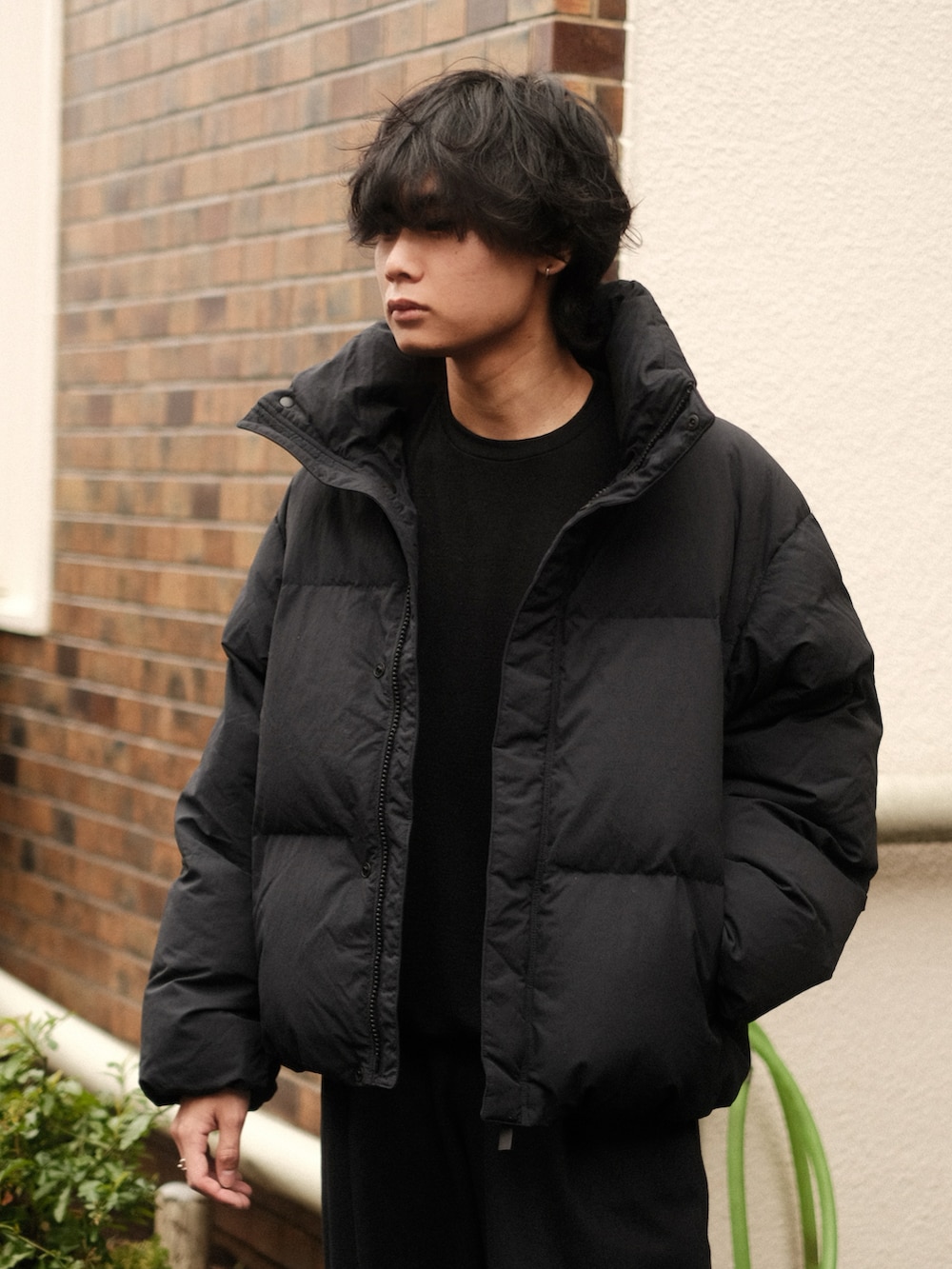 ブラック系のダウンジャケット/コート、ブラック系のTシャツ/カットソー、ブルー系のスラックスを着用したメンズの冬コーディネートの2枚目の写真