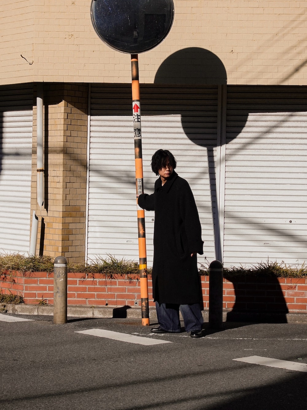 ブラック系のドレスシューズ、ブラック系のその他アウター、ブルー系のデニムパンツを着用したメンズの冬コーディネートの2枚目の写真