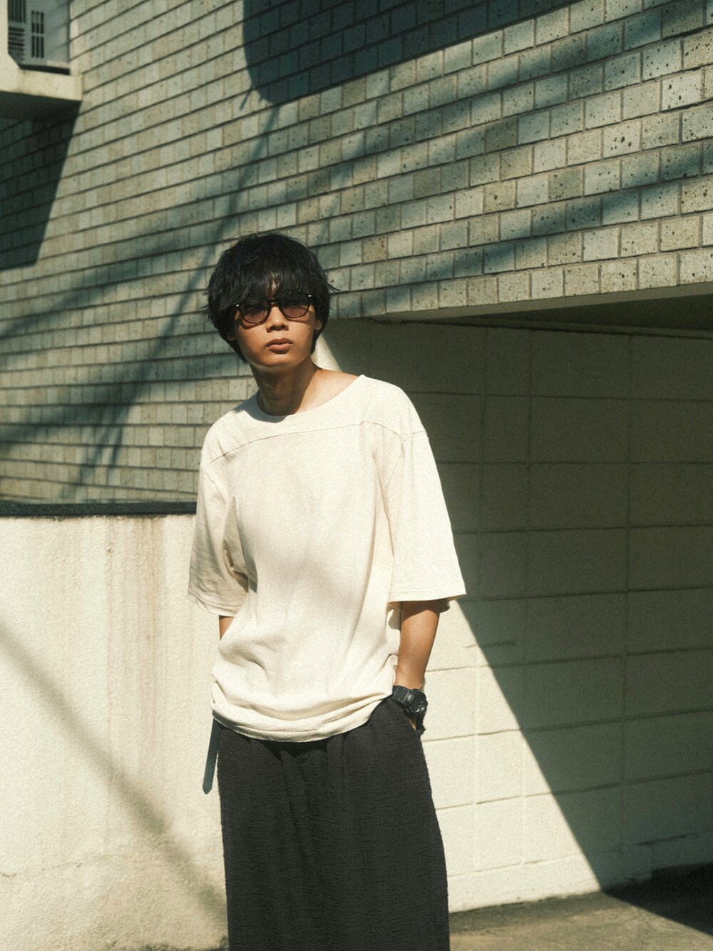ホワイト系のTシャツ/カットソー、グレー系のその他パンツ、ブラック系のサンダルを着用したメンズの夏コーディネートの2枚目の写真