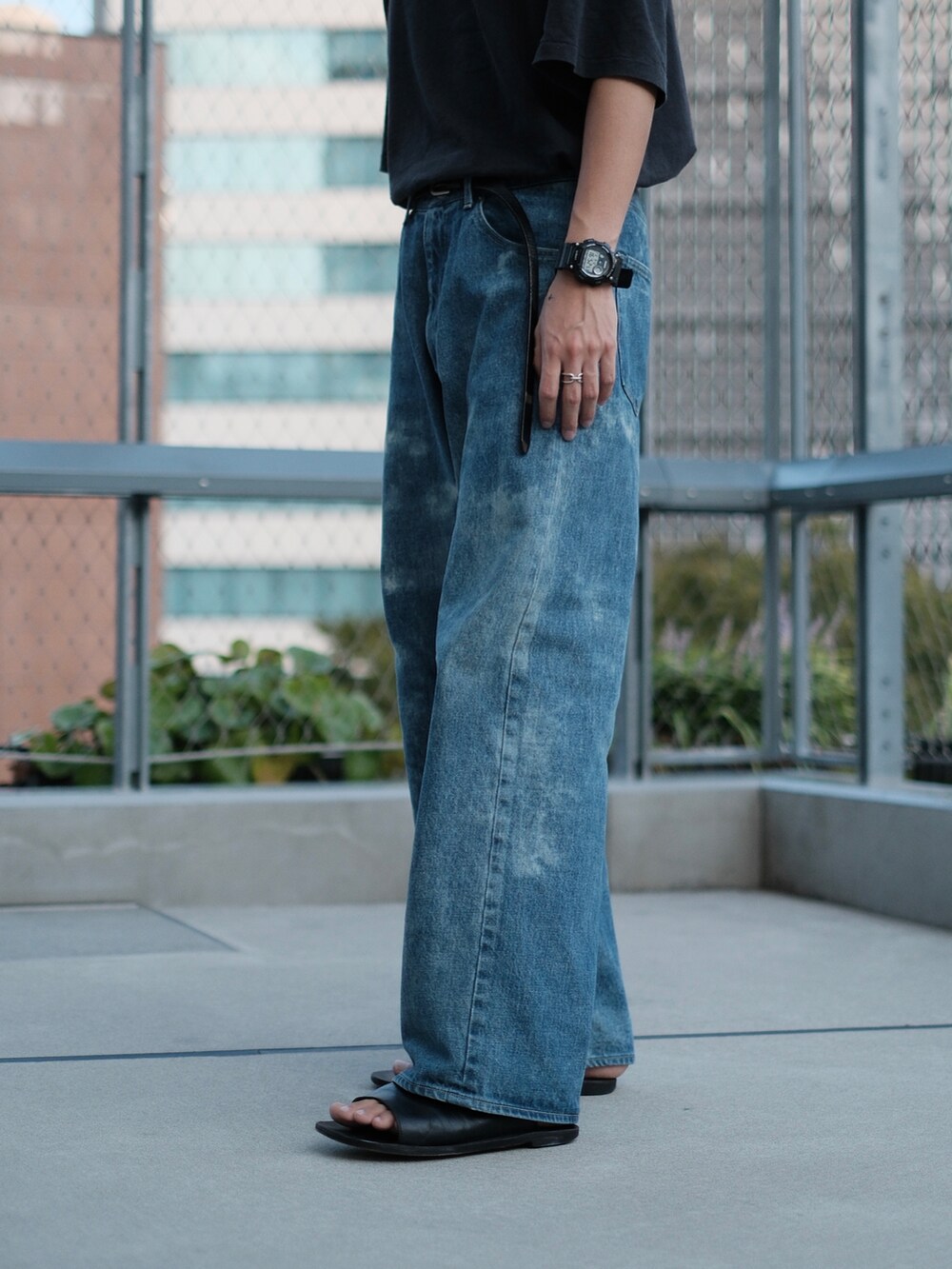 ブラック系のTシャツ/カットソー、ブルー系のデニムパンツ、ブラック系のサンダルを着用したメンズの秋コーディネートの2枚目の写真