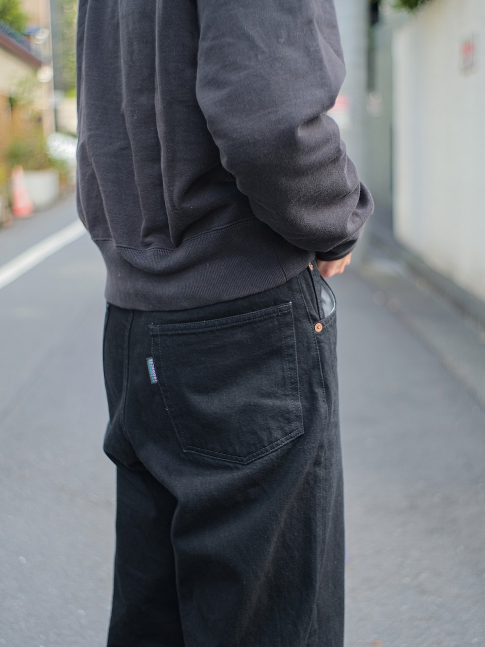 ブラック系のスウェット、ブラック系のデニムパンツ、ブラック系のドレスシューズを着用したメンズの春コーディネートの3枚目の写真