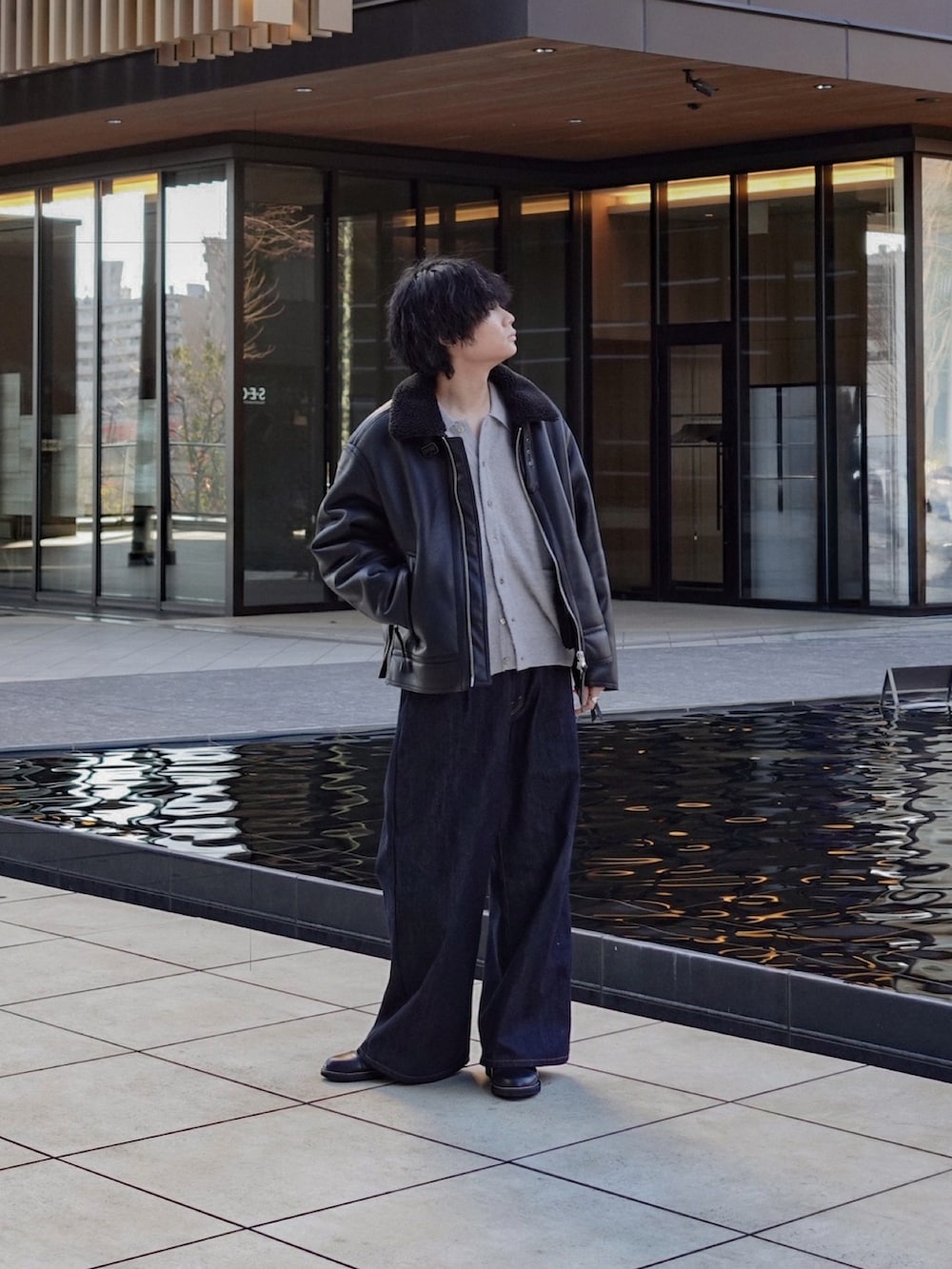 グレー系のニット/セーター、ブラック系のブルゾン、ブルー系のデニムパンツを着用したメンズの冬コーディネートの2枚目の写真