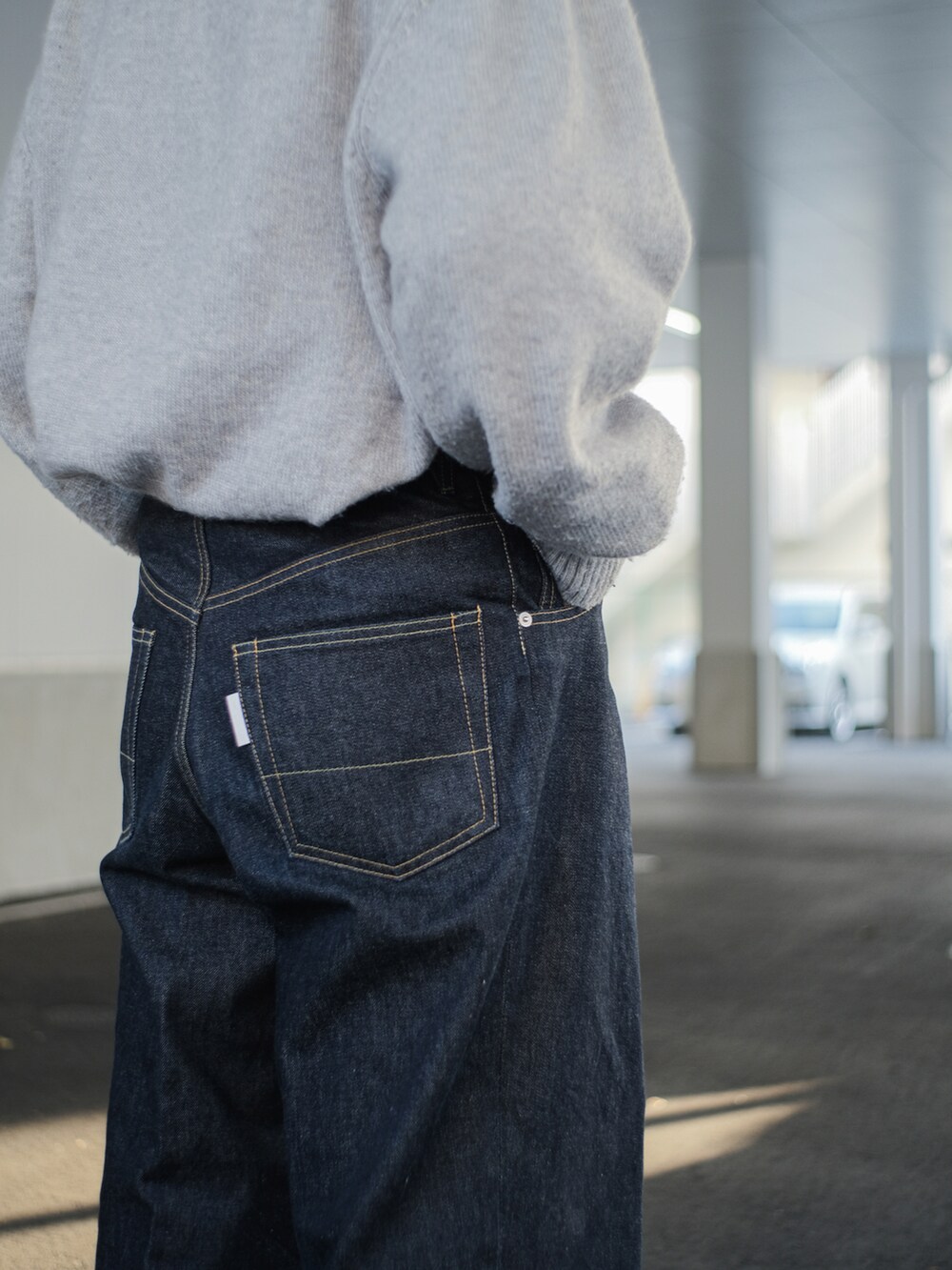 グレー系のニット/セーター、ブルー系のデニムパンツ、ブラック系のドレスシューズを着用したメンズの冬コーディネートの2枚目の写真