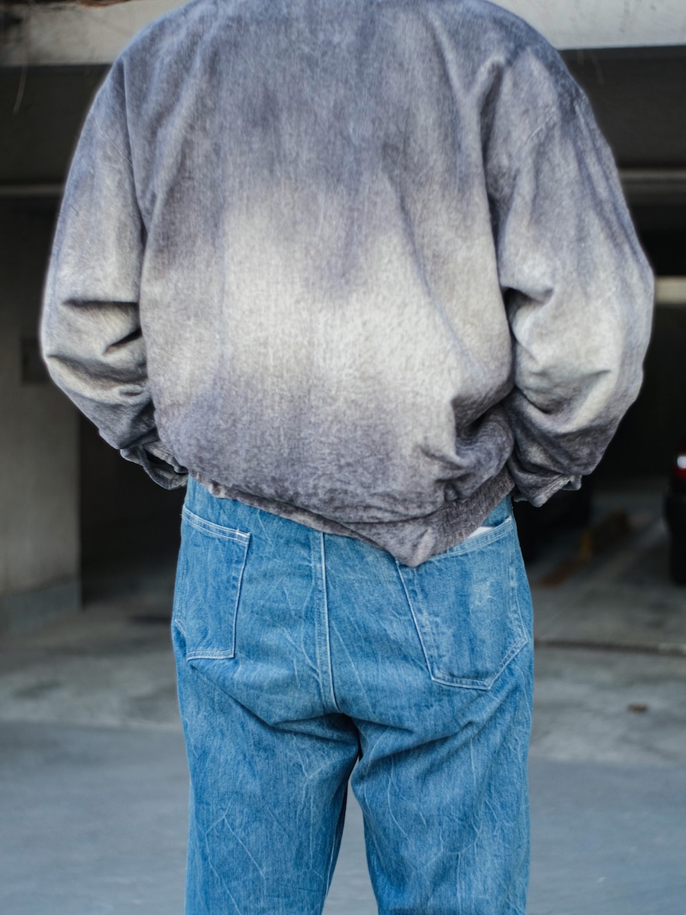 ブルー系のデニムパンツ、グレー系のブルゾン、ブラウン系のサングラスを着用したメンズの冬コーディネートの4枚目の写真