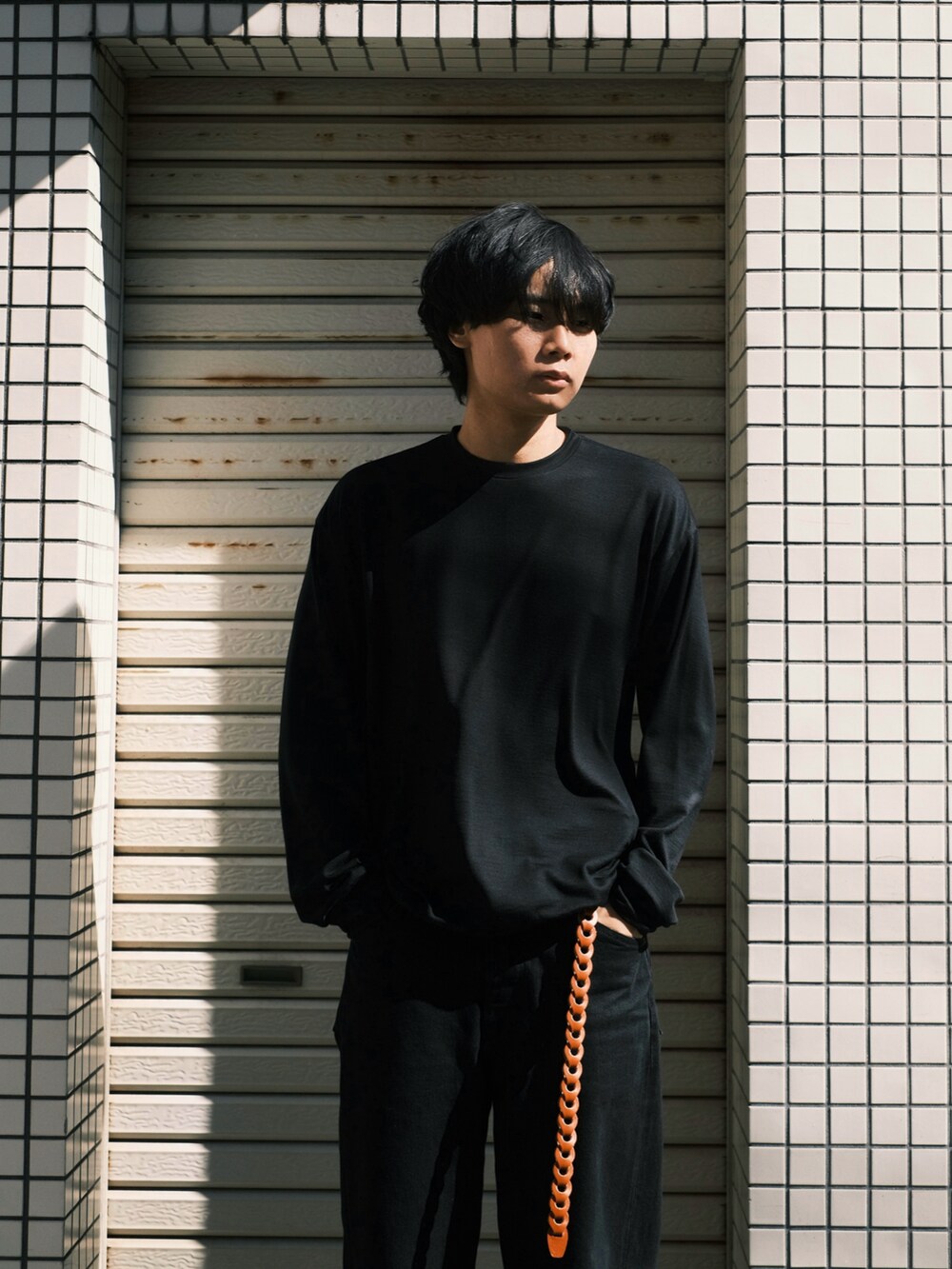 ブラック系のTシャツ/カットソー、ブラック系のデニムパンツ、ブラック系のスニーカーを着用したメンズの秋コーディネートの2枚目の写真