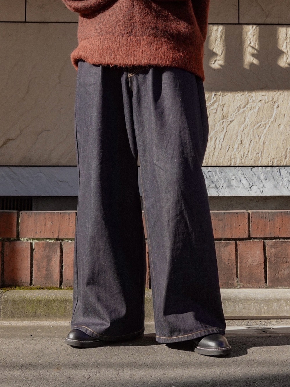 ブルー系のデニムパンツ、ブラック系のドレスシューズ、ブラウン系のニット/セーターを着用したメンズの冬コーディネートの2枚目の写真