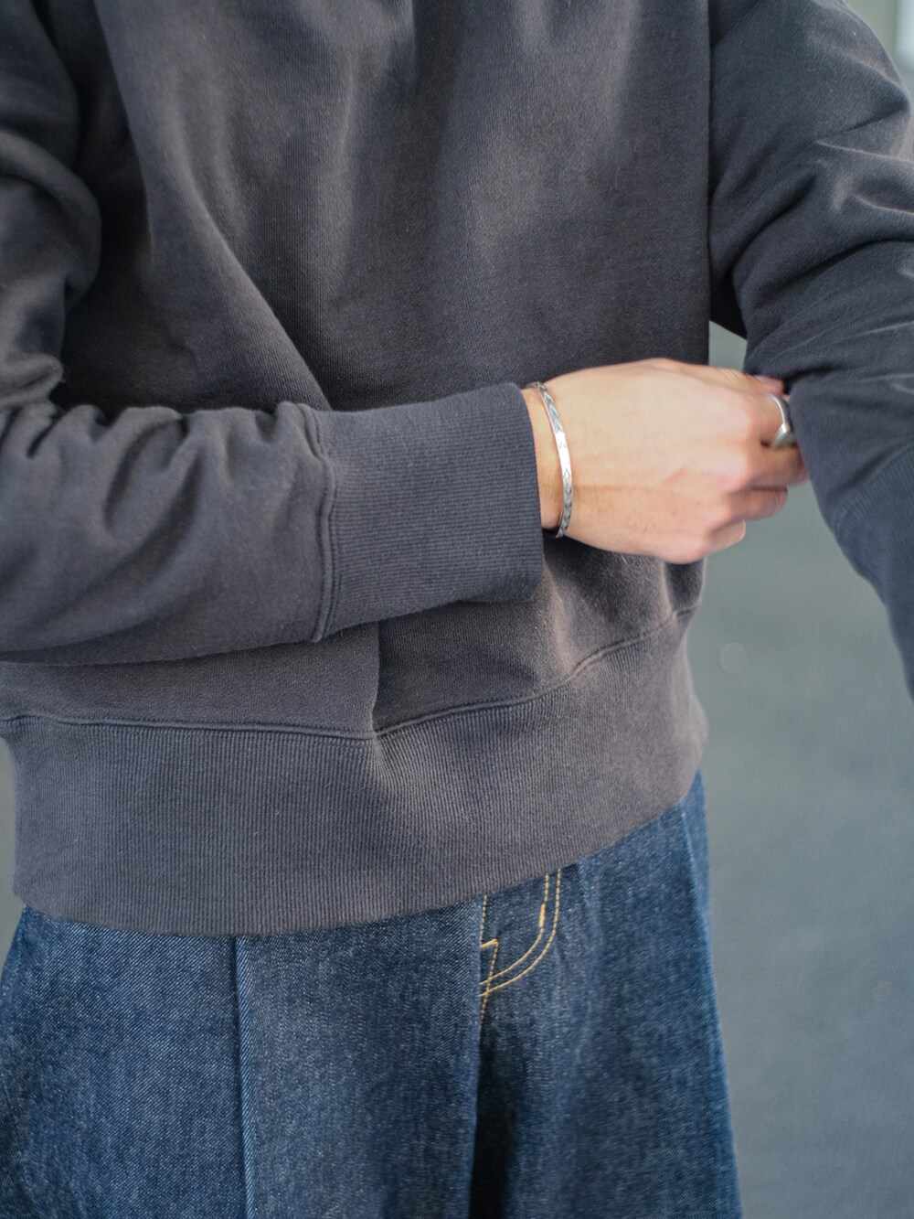 ブラック系のスウェット、ブルー系のデニムパンツ、ブラック系のドレスシューズを着用したメンズの春コーディネートの4枚目の写真