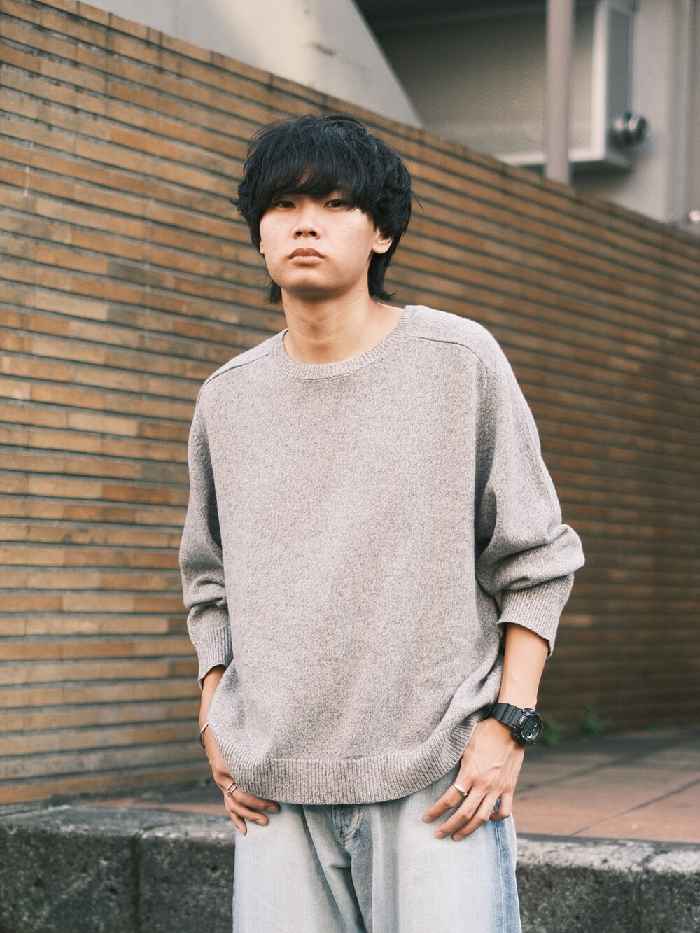 ブラック系のスニーカー、ブルー系のデニムパンツ、グレー系のニット/セーターを着用したメンズの秋コーディネートの2枚目の写真