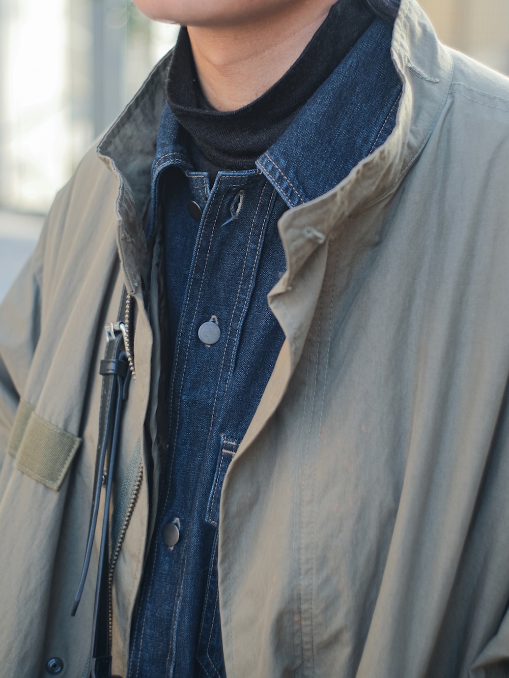 グリーン系のモッズコート、ブルー系のシャツ/ブラウス、ブラック系のデニムパンツを着用したメンズの冬コーディネートの3枚目の写真