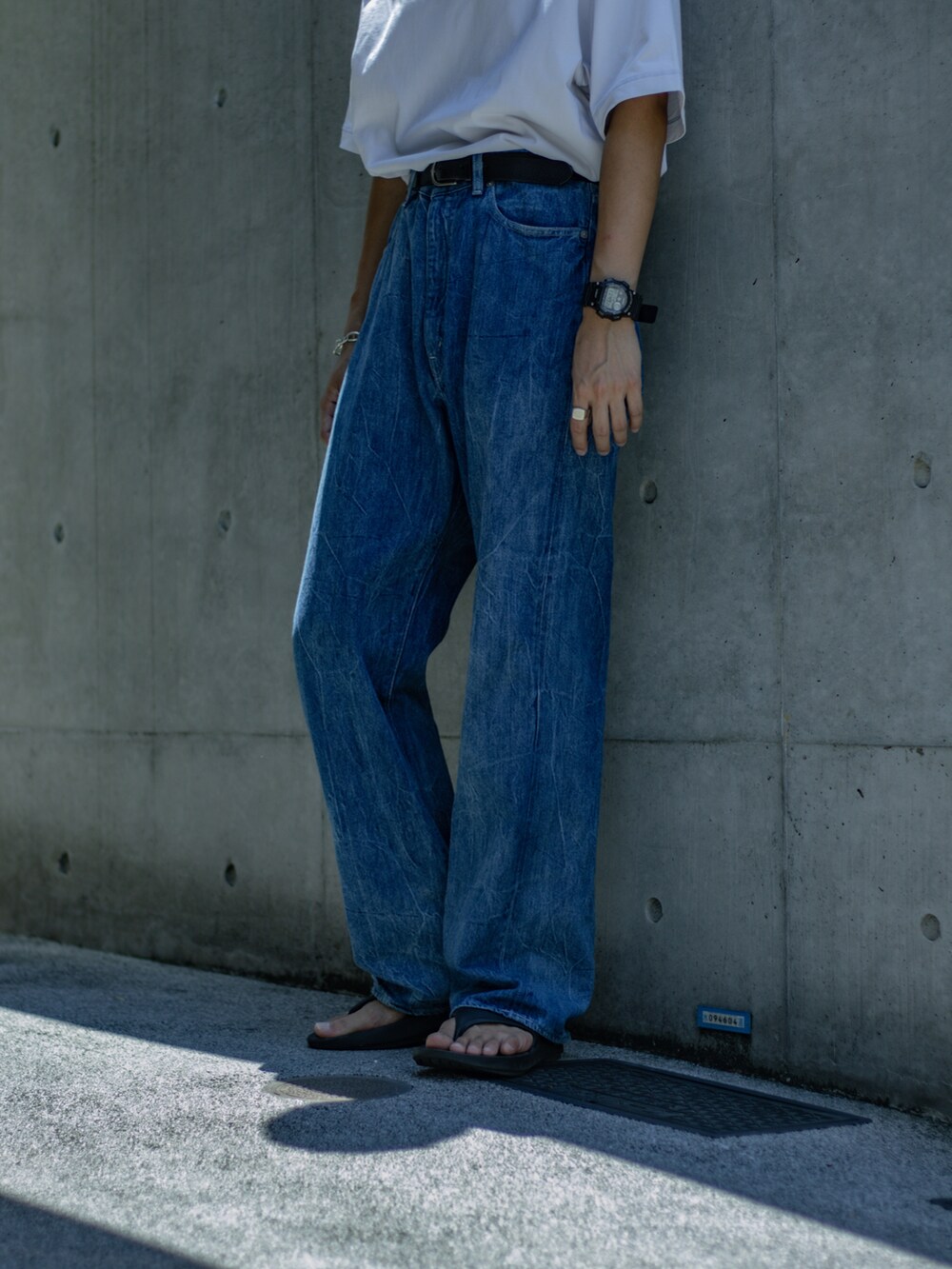 ホワイト系のTシャツ/カットソー、ブルー系のデニムパンツ、ブラック系のサンダルを着用したメンズの夏コーディネートの2枚目の写真