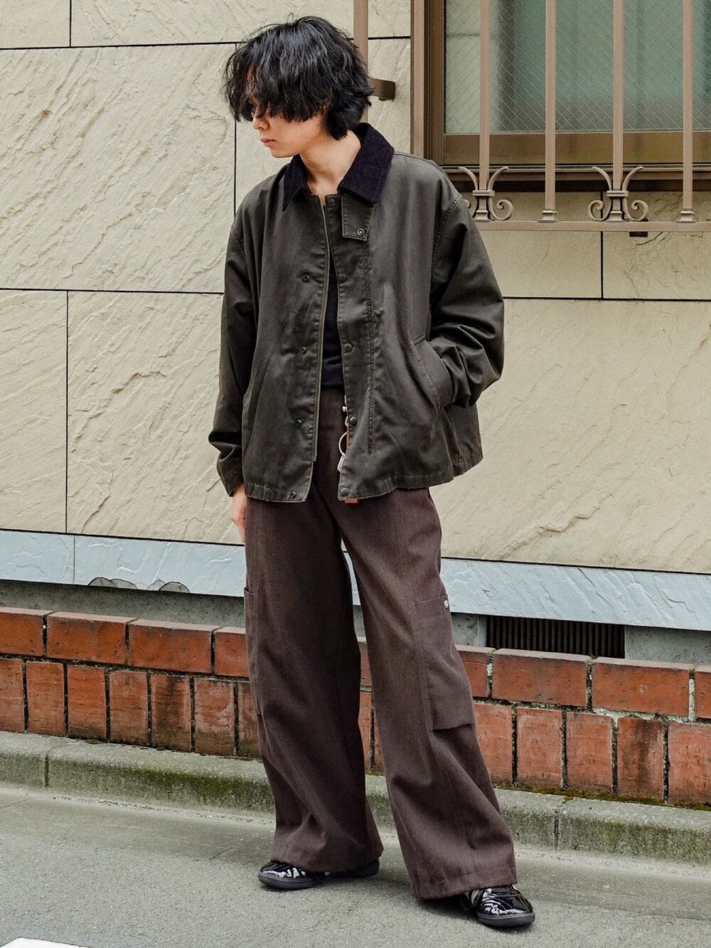 ブラウン系のブルゾン、ブラック系のTシャツ/カットソー、ブラック系のスニーカーを着用したメンズの秋コーディネートの2枚目の写真