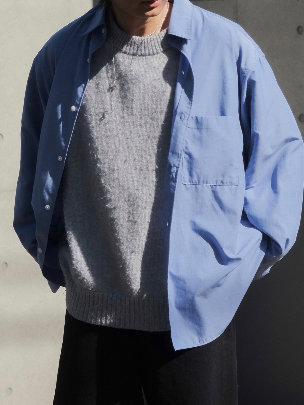 ブルー系のシャツ/ブラウス、グレー系のニット/セーター、ブラック系のデニムパンツを着用したメンズの春コーディネートの3枚目の写真