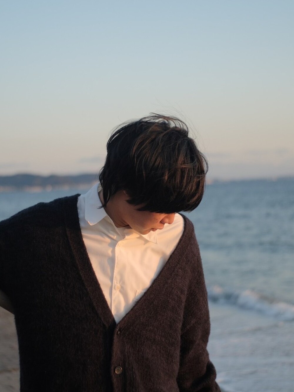 ブラック系のカーディガン/ボレロ、ホワイト系のシャツ/ブラウス、ブルー系のデニムパンツを着用したメンズの冬コーディネートの2枚目の写真