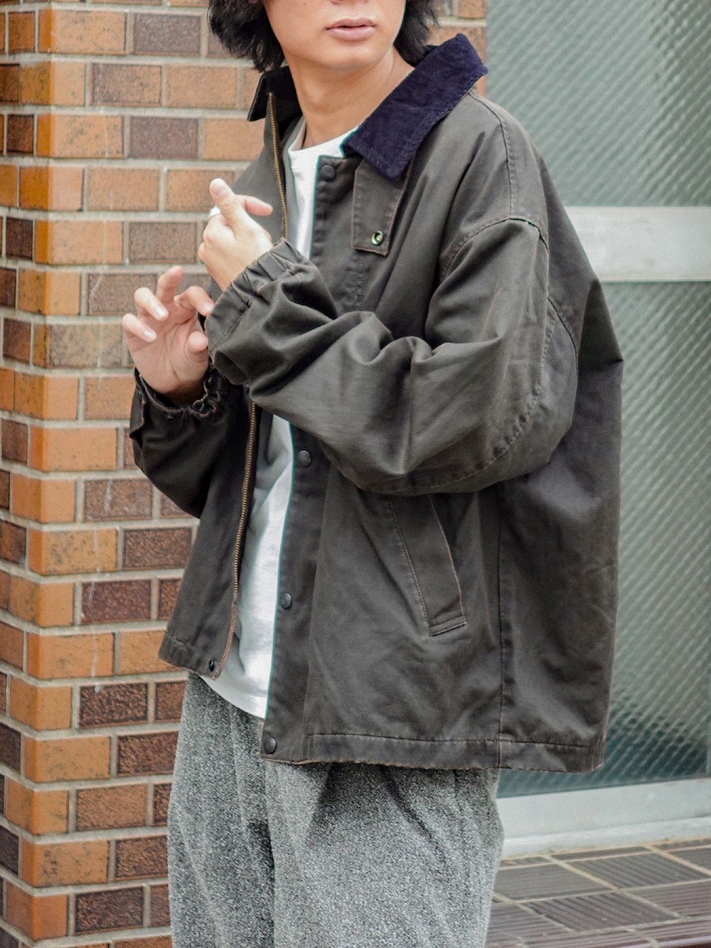 ホワイト系のTシャツ/カットソー、ブラウン系のブルゾン、グレー系のスラックスを着用したメンズの秋コーディネートの2枚目の写真