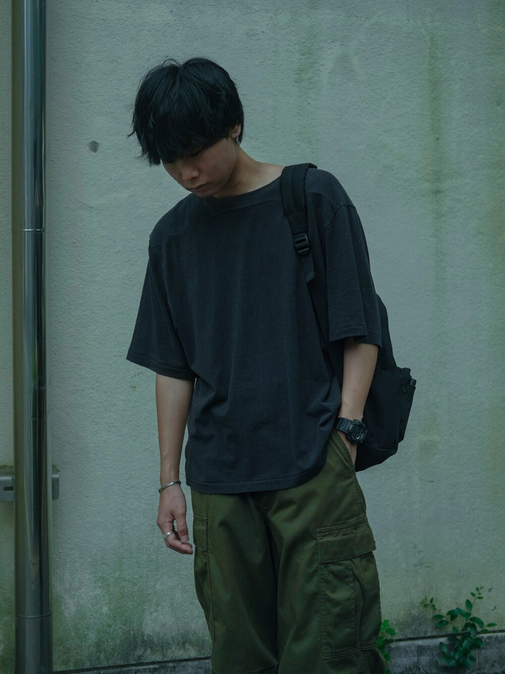 ブラック系のTシャツ/カットソー、ブラック系のバックパック/リュック、グリーン系のカーゴパンツを着用したメンズの夏コーディネートの2枚目の写真